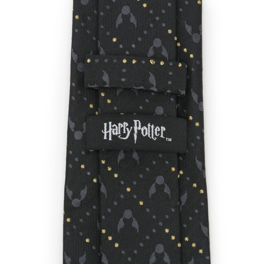 Harry Potter Golden Snitch Black Silk Men’s Tie featuring a black background with a repeating pattern of gray winged snitches, gold dots, and an officially licensed logo label on the back.