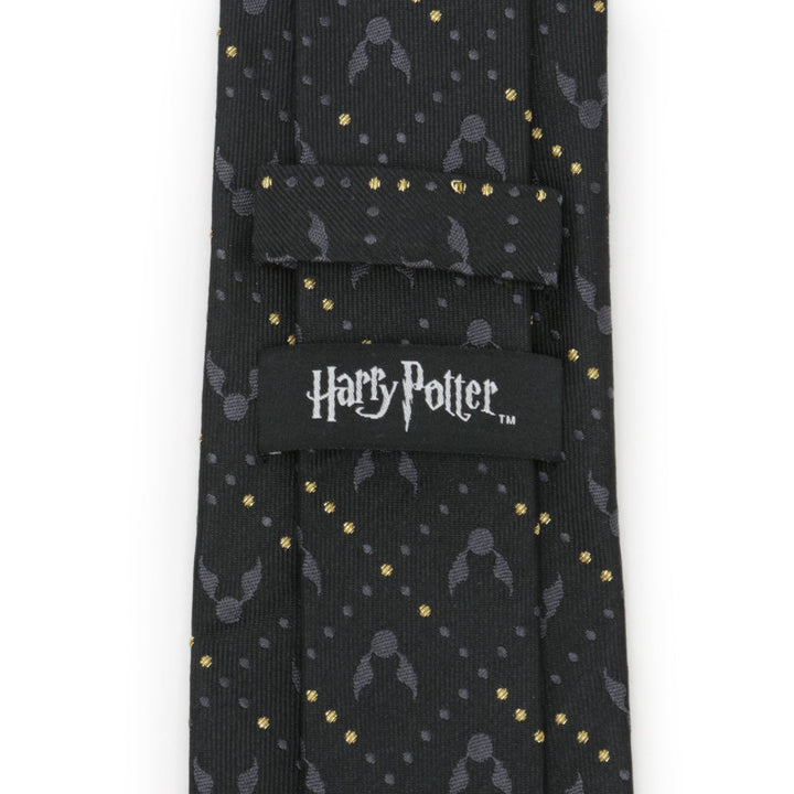 Harry Potter Golden Snitch Black Silk Men’s Tie featuring a black background with a repeating pattern of gray winged snitches, gold dots, and an officially licensed logo label on the back.