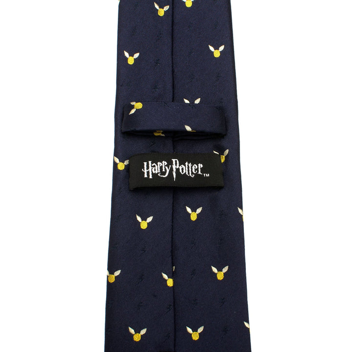 Dark blue Harry Potter Golden Snitch Dot Tie patterned with small gold and white winged snitch icons, featuring a black logo label on the back.