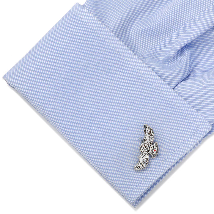 A silver-toned Harry Potter Hedwig Owl Cufflinks piece attached to a light blue, diagonally striped shirt cuff.