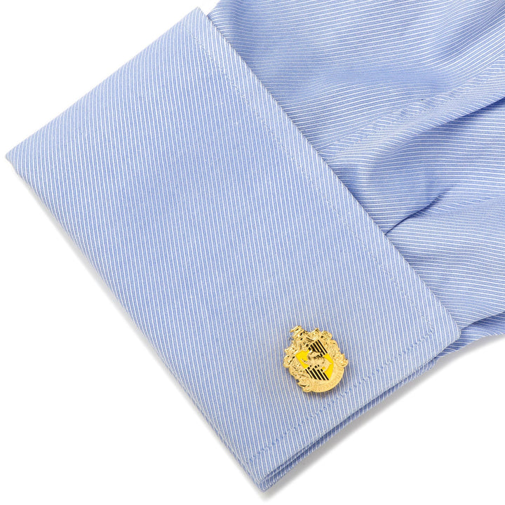 Harry Potter Hufflepuff Crest Cufflinks in gold-toned metal with yellow and black details attached to a light blue dress shirt cuff.