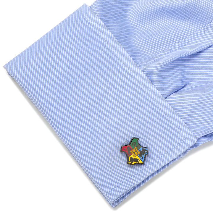 A light blue dress shirt cuff fastened with Harry Potter Hogwarts Shield Cufflinks featuring the four house symbols.