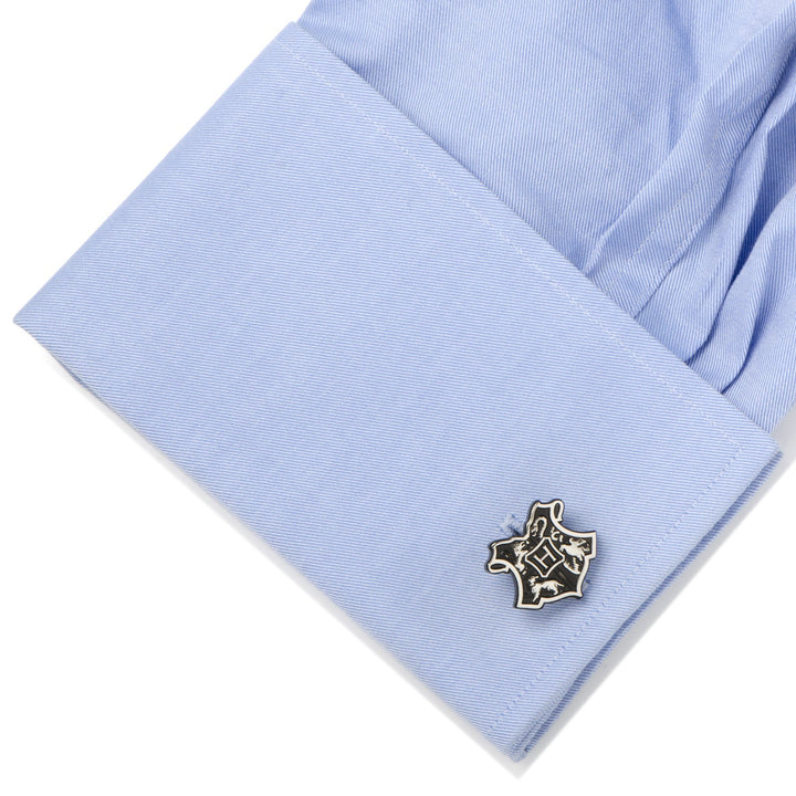 A Harry Potter Hogwarts 3D Crest Cufflink attached to a light blue dress shirt cuff.