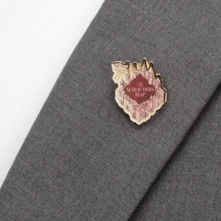 A red and gold Harry Potter Marauder’s Map lapel pin shaped like a castle, featuring the text “The Marauder’s Map” attached to a gray suit jacket.