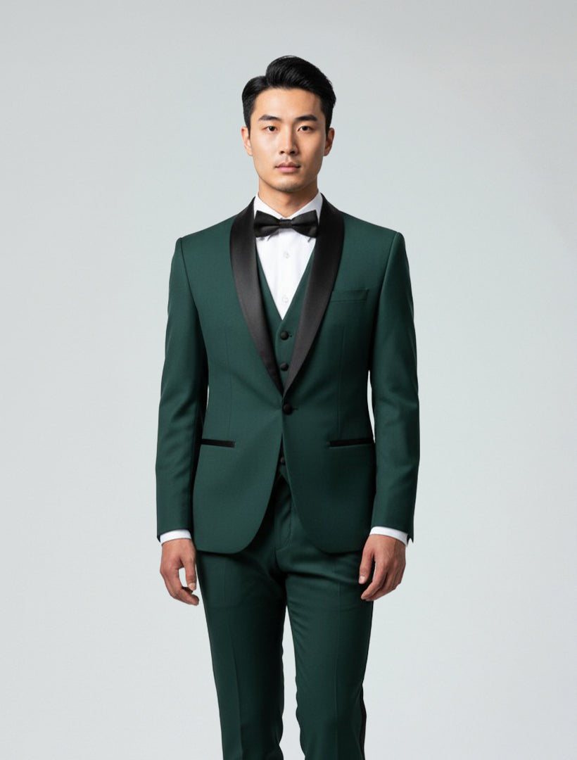 A man stands facing forward against a plain light background, wearing the Gino Vitale Men's Hunter Green Shawl Lapel Tailored Fit Tuxedo with a white dress shirt and black bow tie.