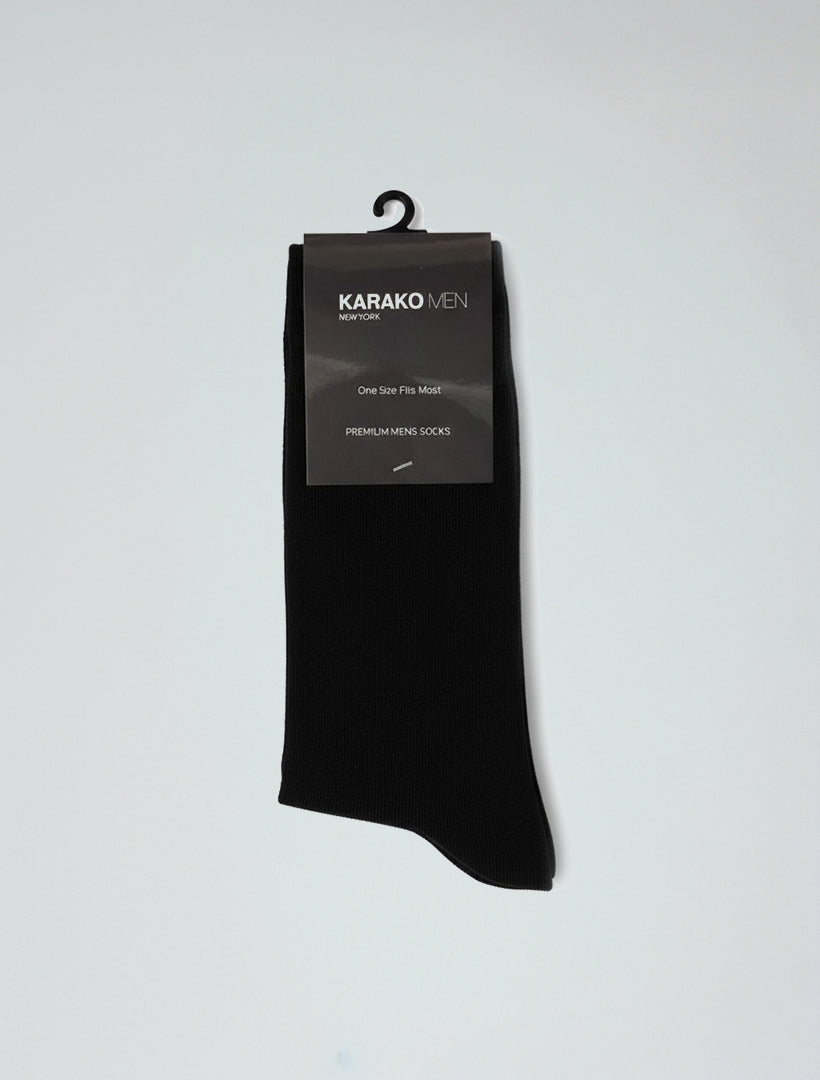 A pair of Karako Men Onyx Black Basic Dress Socks in retail packaging labeled "KARAKO MEN," featuring ribbed cuffs, elastic stretch for comfort, a hanging hook, and a "One Size Fits Most" tag.