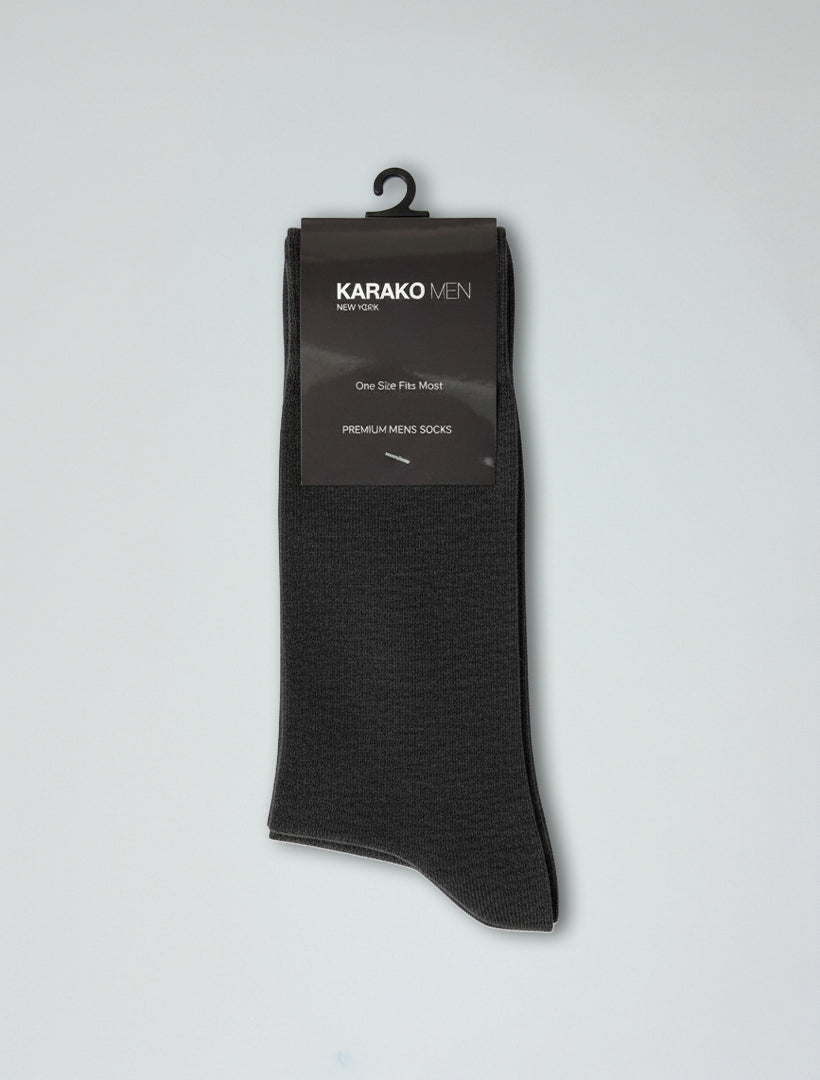 A single pair of Karako Men Charcoal Basic Dress Socks is displayed on a hanger with a label reading "Karako Men," featuring ribbed stay-up cuffs for comfort and a secure fit.
