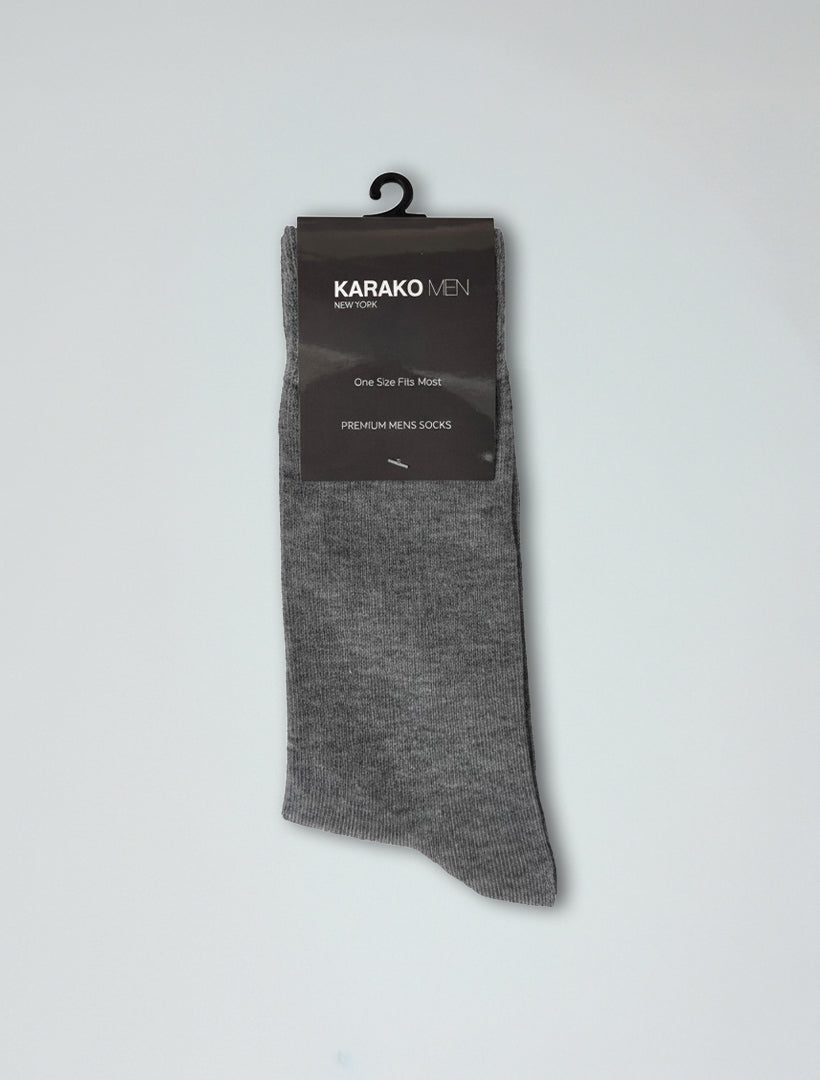 A pair of Karako Men Heather Grey Basic Dress Socks with ribbed stay-up cuffs hangs on a black plastic hanger against a plain background.