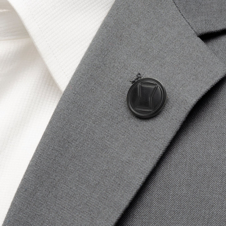 Round black Marvel Black Widow Lapel Pin attached to a gray suit jacket lapel over a white shirt.