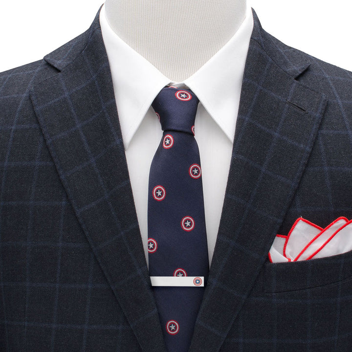 A silver-plated Marvel Captain America Shield Tie Bar worn on a dark navy blue tie with a repeating shield pattern.