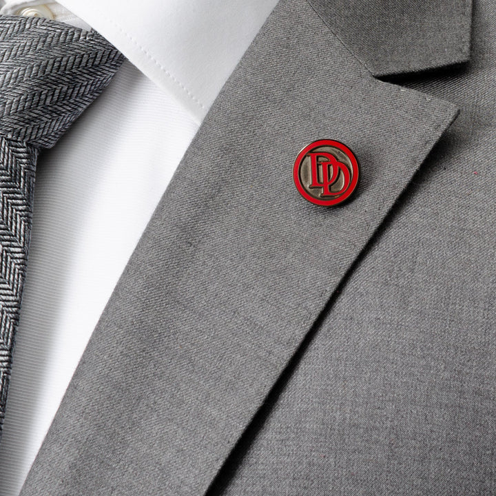 A round, red and black Marvel Daredevil Embossed Logo Lapel Pin fastened to the lapel of a grey suit jacket.