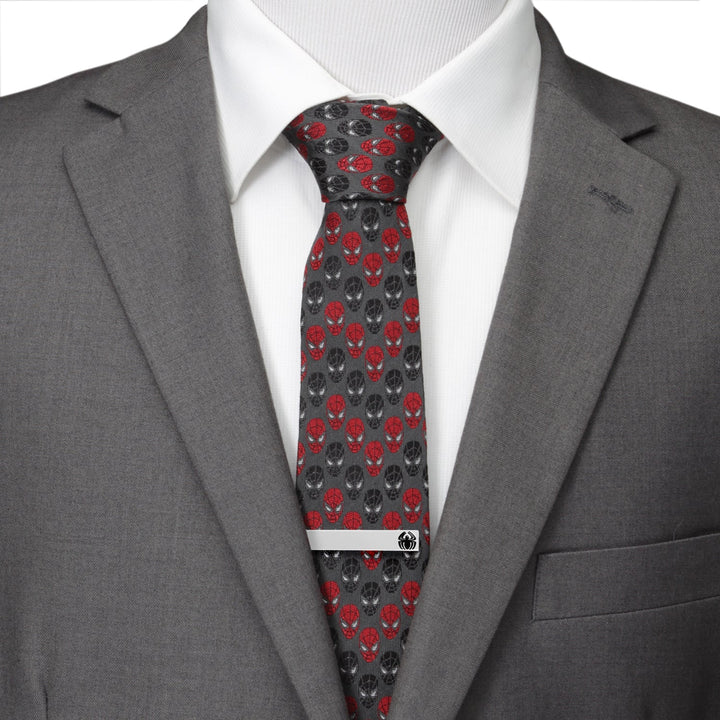 A silver-toned Marvel Spider-Man Spider Tie Bar featuring a small black spider emblem, worn on a dark grey tie with a red and black mask pattern, a white dress shirt, and a grey suit jacket.
