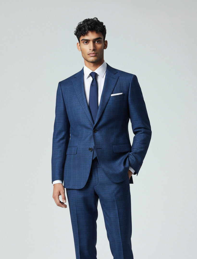 A man in a Gianco Ferro Men's Navy Glen Plaid Slim Fit Suit, white dress shirt, and navy tie stands against a plain light background with one hand in his pocket.