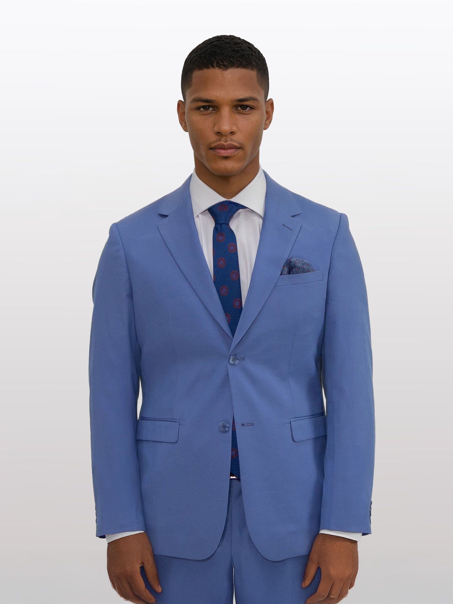 A man in a slim fit Men's Azure Blue Suit by Gianco Ferro, complemented by a white shirt and a patterned tie, stands elegantly against a plain background, demonstrating the comfort of its stretch armhole feature.