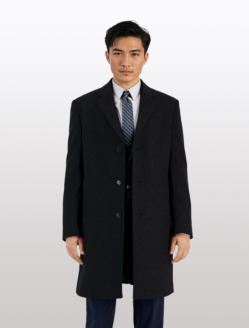 A man in a Michael Kors Men’s Black Classic Fit Cashmere-Blend Three-Button Overcoat stands facing forward against a plain light background.