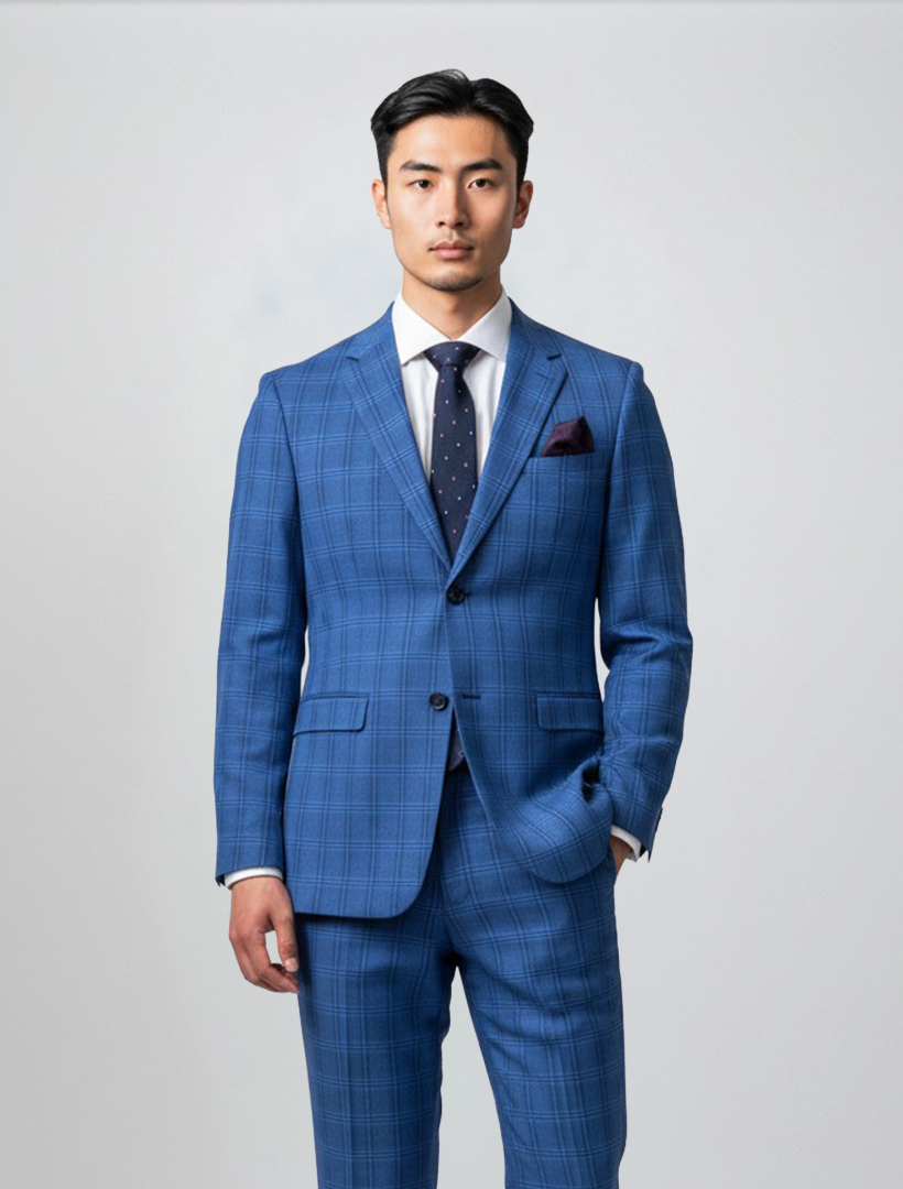A man stands facing forward against a plain light gray background, wearing the Gianco Ferro Men’s Blue with Light Blue and Black Windowpane Slim Fit Suit, tailored from premium Tetron Rayon and paired with a white dress shirt, navy polka dot tie, and pocket square.