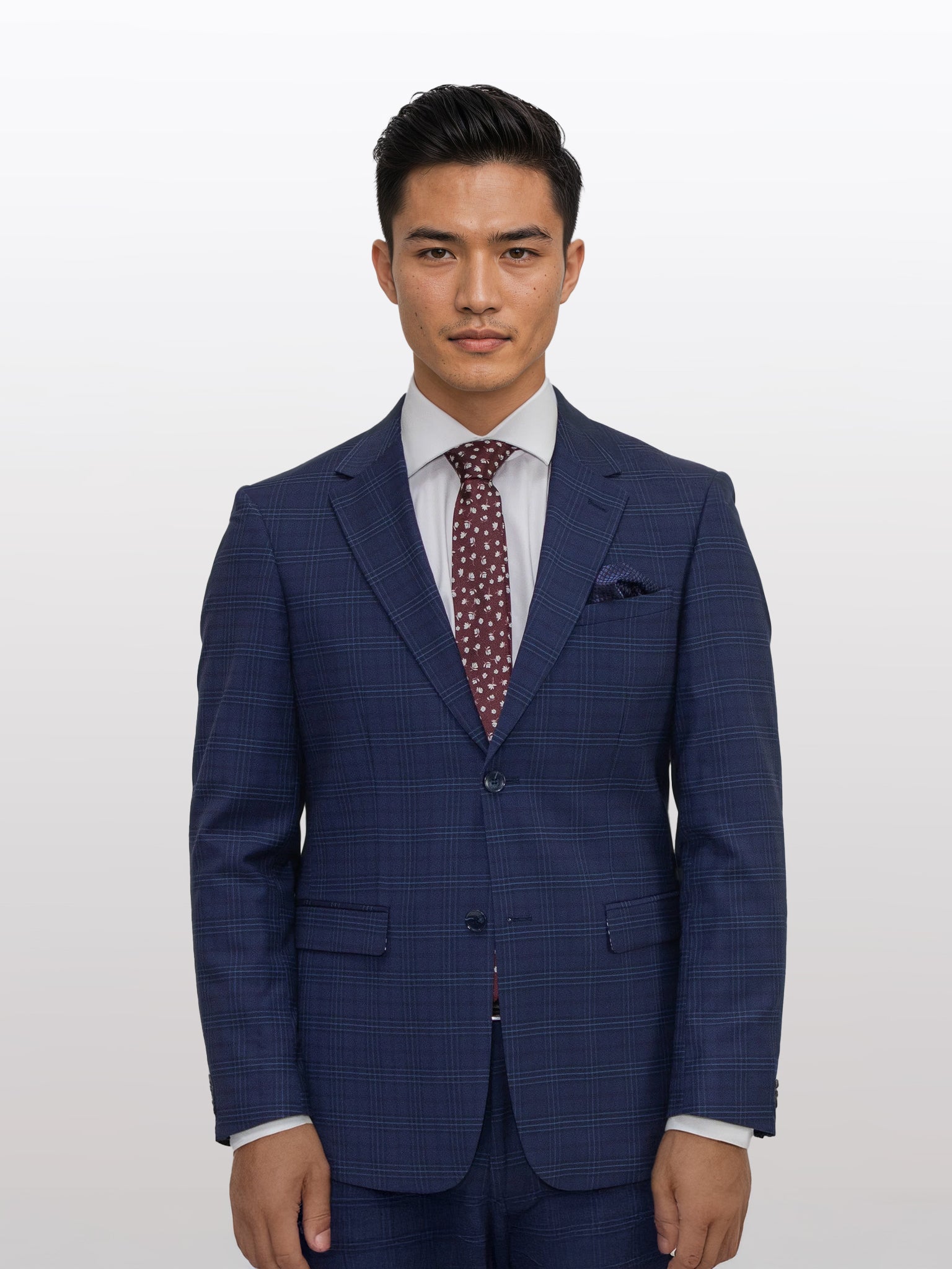 A man in a Gianco Ferro Men's Dark Blue Tartan Slim Fit Suit, complemented by a white shirt and red polka dot tie, stands against a plain background.