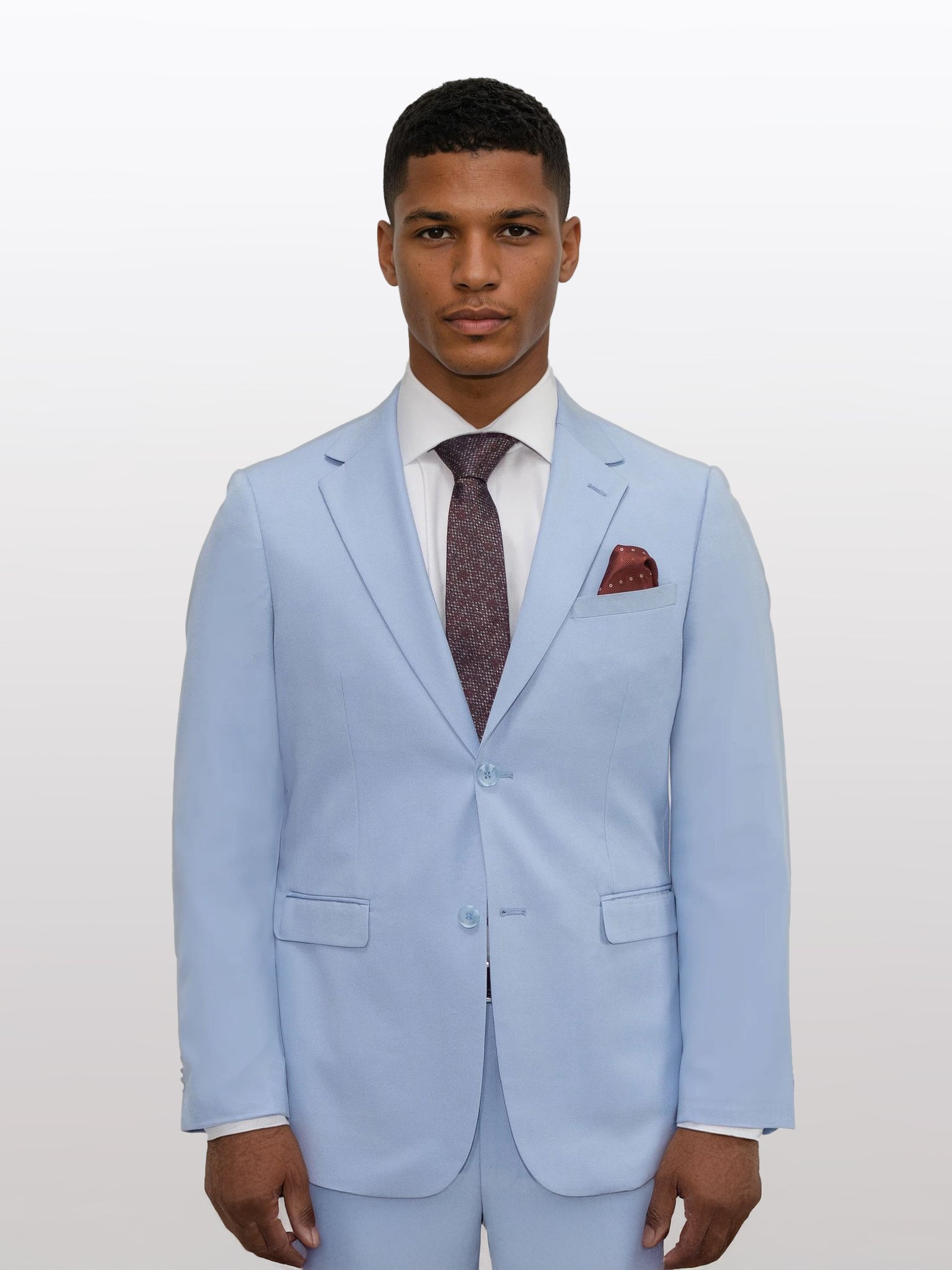 A gentleman wearing a Gianco Ferro Men's Light Blue Solid Slim Fit Suit, paired with a crisp white shirt, a dark patterned tie, and an elegant pocket square, stands against a plain backdrop.