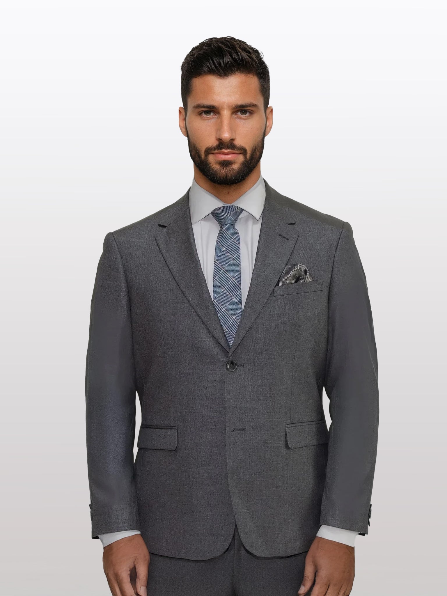 A man with a beard is dressed in a Men's Medium Grey Solid Slim Fit Suit by Gianco Ferro, paired with a white shirt and a blue patterned tie, standing against a plain white background.