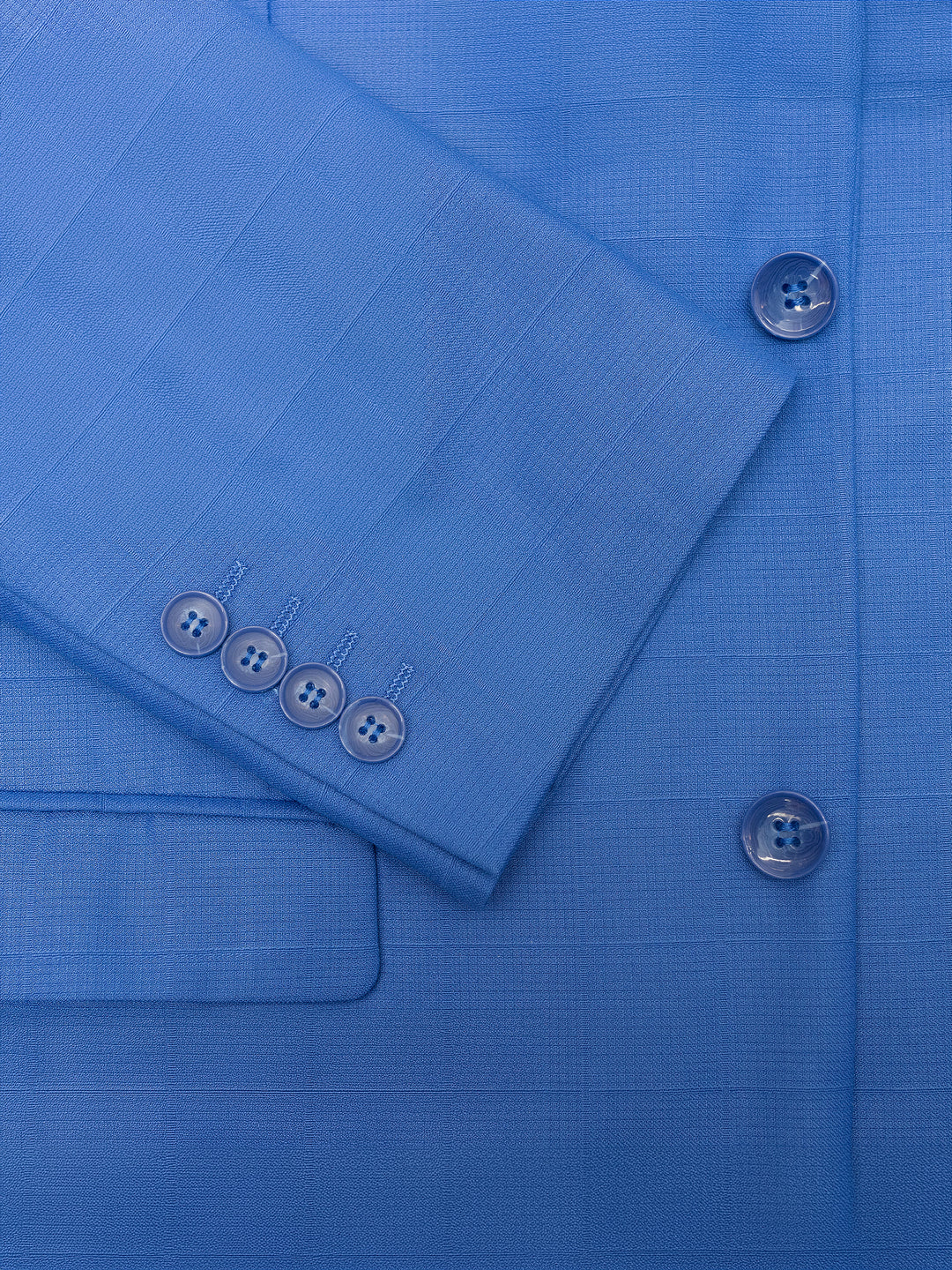 Close-up of a royal blue debossed windowpane suit jacket from Gianco Ferro, highlighting the sleeve and front buttons along with the intricate texture and stitching details. This Men&
