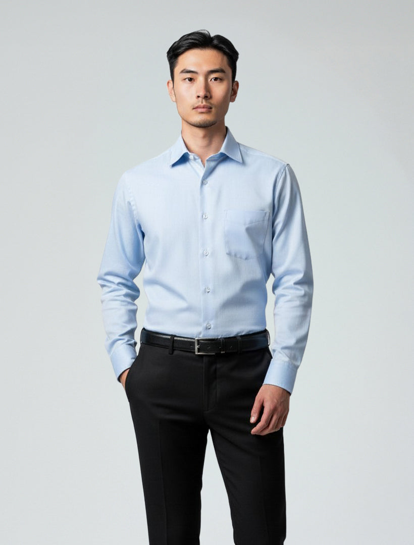A man wears a Karako Men Light Blue Dress Shirt and black pants, standing facing forward against a plain, light background.
