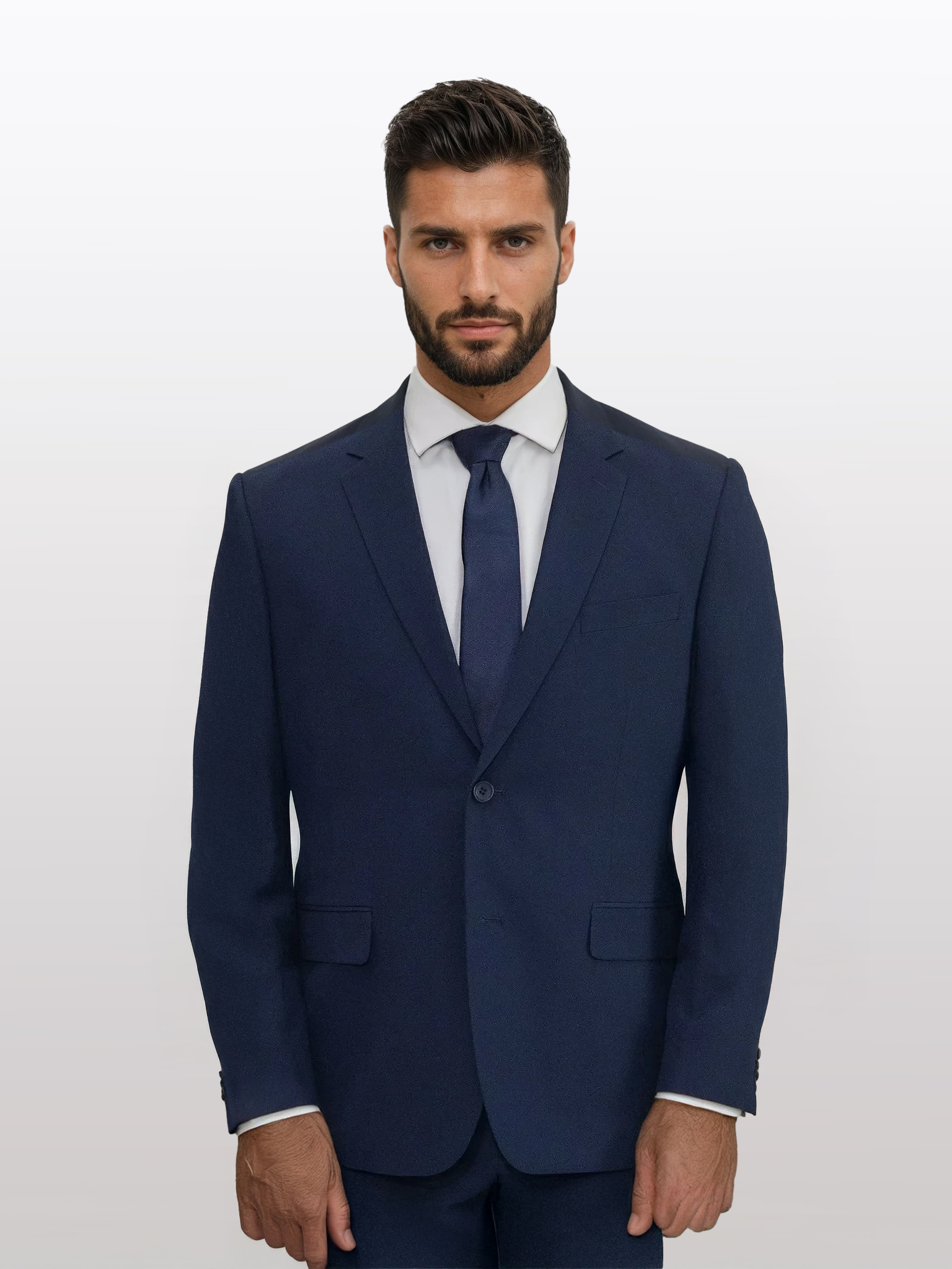 A man showcased in the Mens Navy Suit from Karako Men, impeccably paired with a white shirt and coordinating navy tie, stands against a plain white backdrop—an ideal ensemble for weddings or as an elegant choice among prom suits.