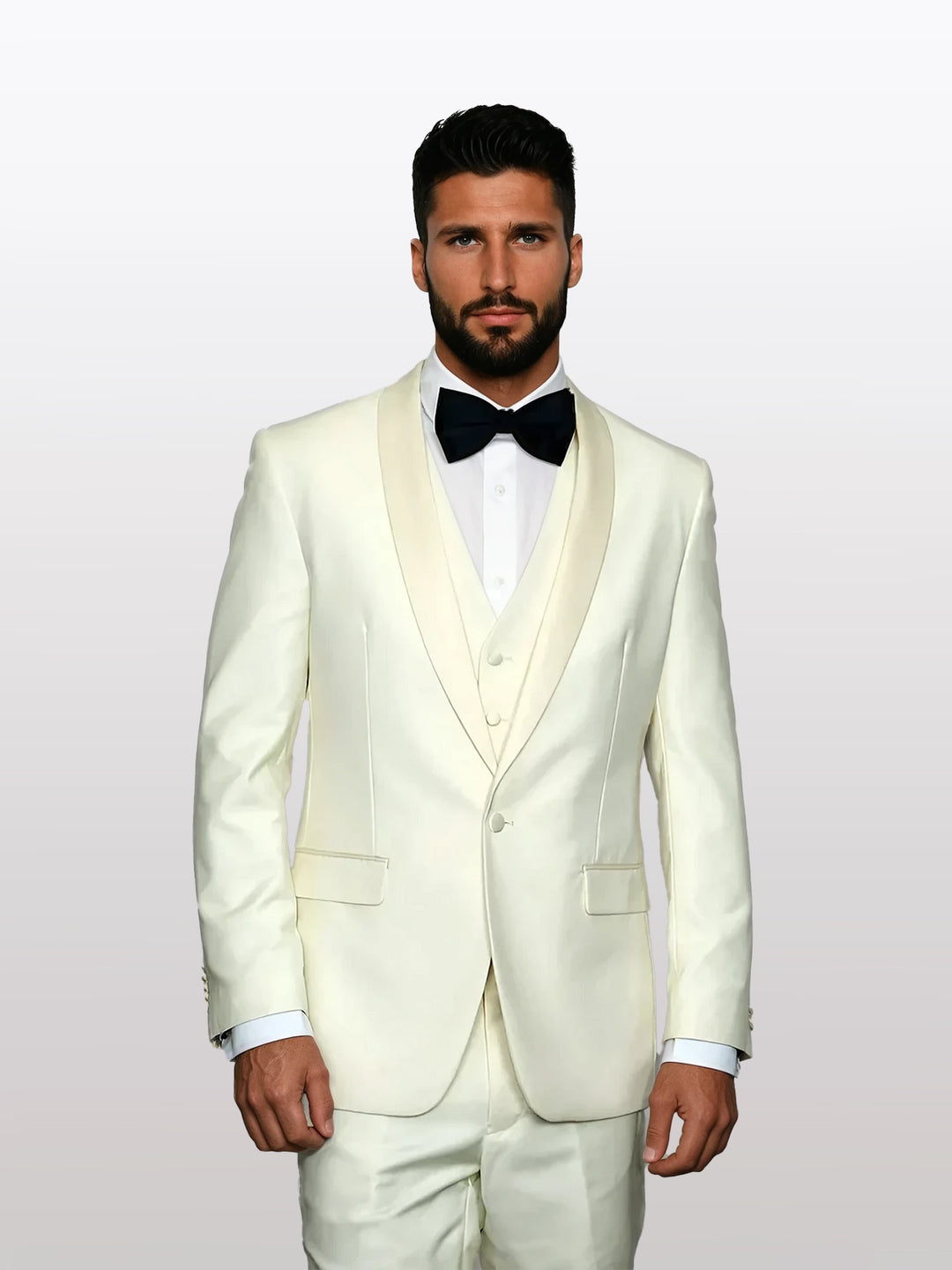 A man exudes sophistication in a Statement men's off-white with white lapel vested tuxedo made of 100% wool, paired with a classic black bow tie against a muted gray background.