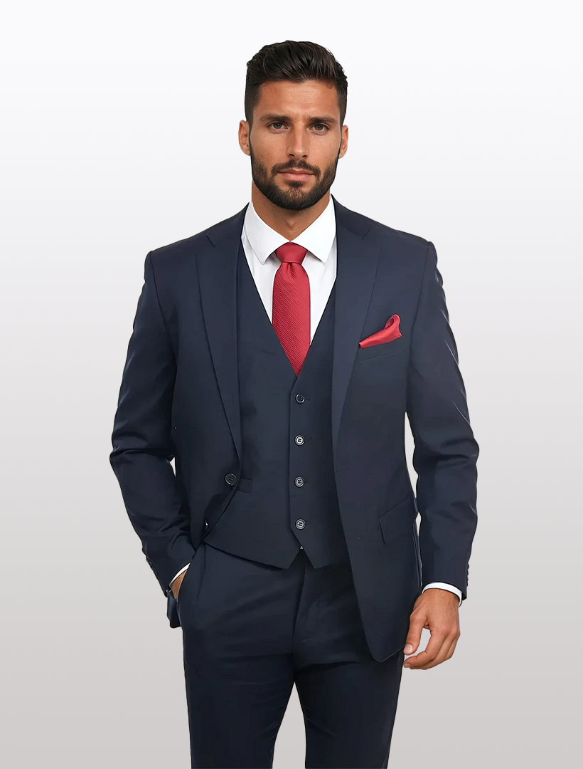 A man wearing the Navy Men's Slim-Fit Suit Separates Jacket by Karako Separate with a matching vest, white dress shirt, red tie, and red pocket square stands against a plain light background.