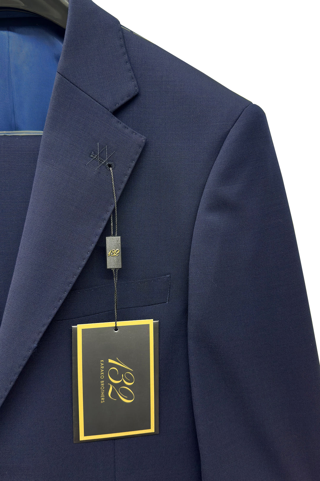 Men’s Navy Wool Suit by 132 displayed on a hanger with a black and yellow price tag attached to the lapel.