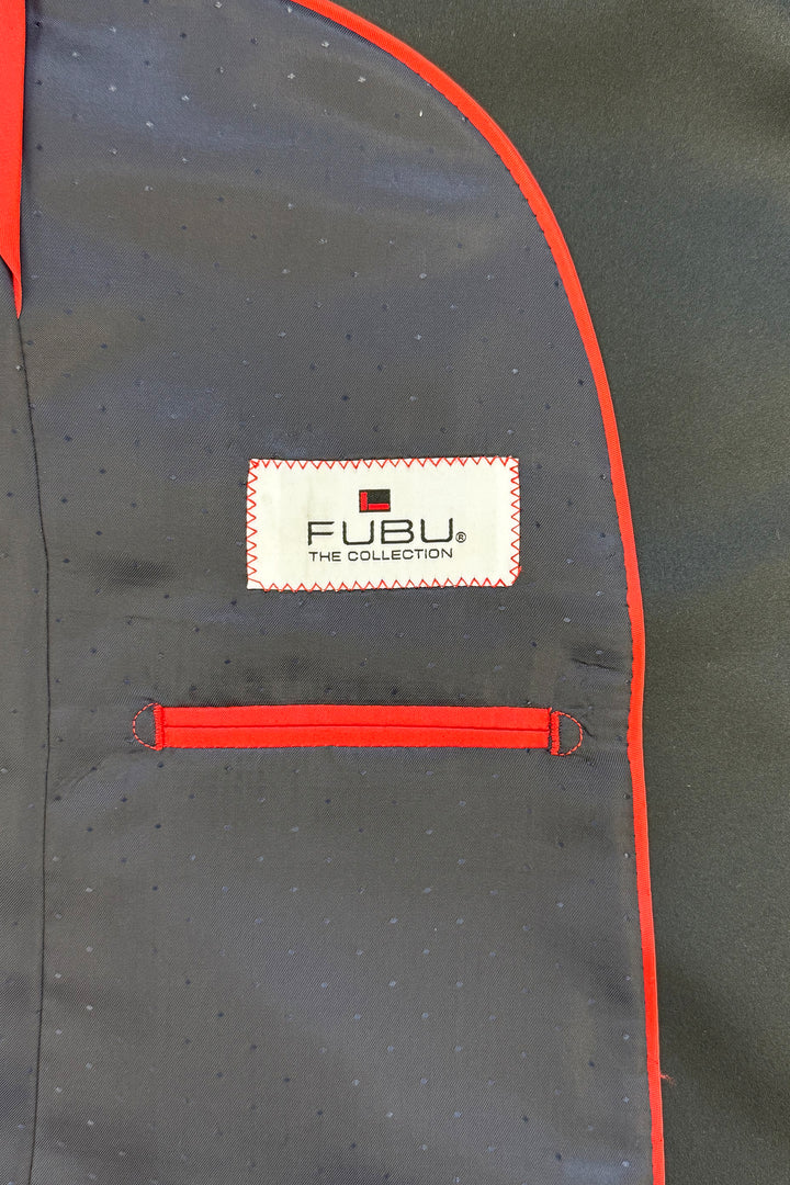 Close-up of the interior pocket with red trim on the Fubu The Colle Classic Notch Lapel Navy Slim-Fit Tuxedo, featuring a label on dark fabric.