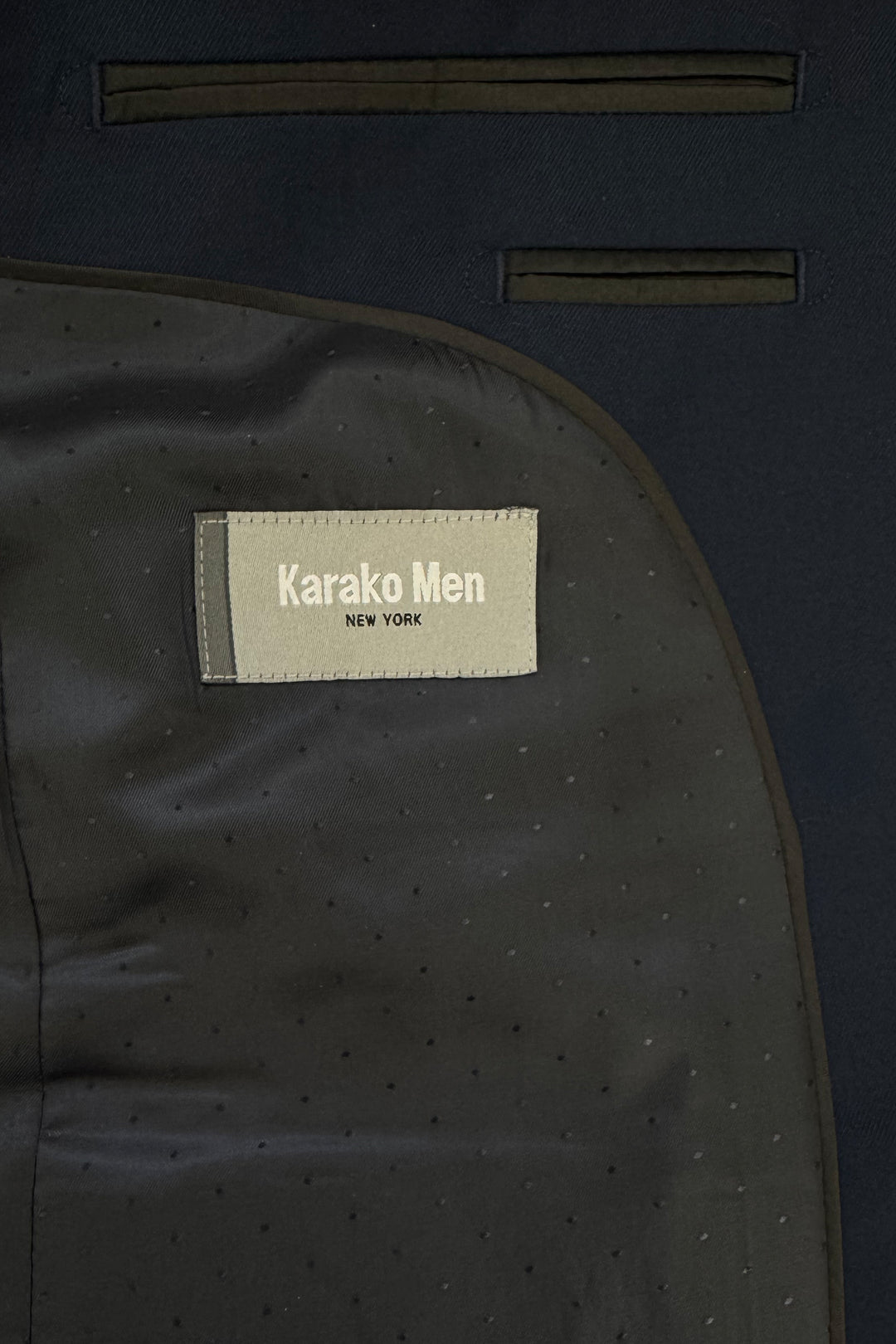 Close-up of the inside of a Mens Navy Suit by Karako Men, showing the label sewn onto the lining—ideal for anyone seeking a stylish suit for prom or weddings.