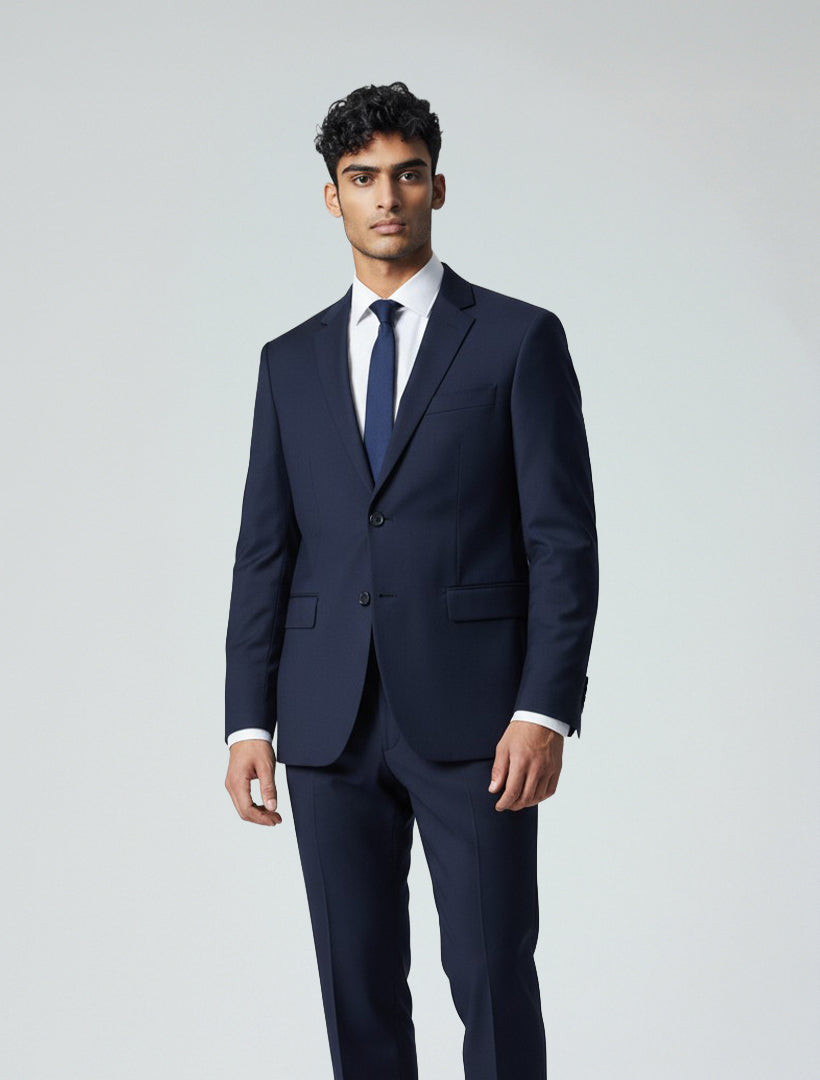 A man in the Karako Men Mens Navy Suit, paired with a white shirt and navy tie, stands against a light background—an ideal, stylish wedding suit choice for men.