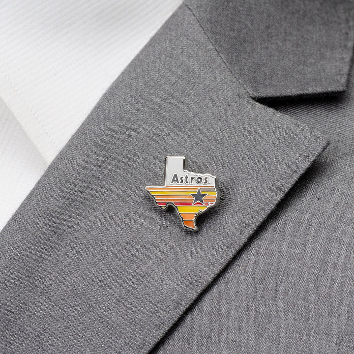 An MLB Houston Astros Tequila Sunrise Lapel Pin shaped like Texas, pinned to a grey suit jacket.
