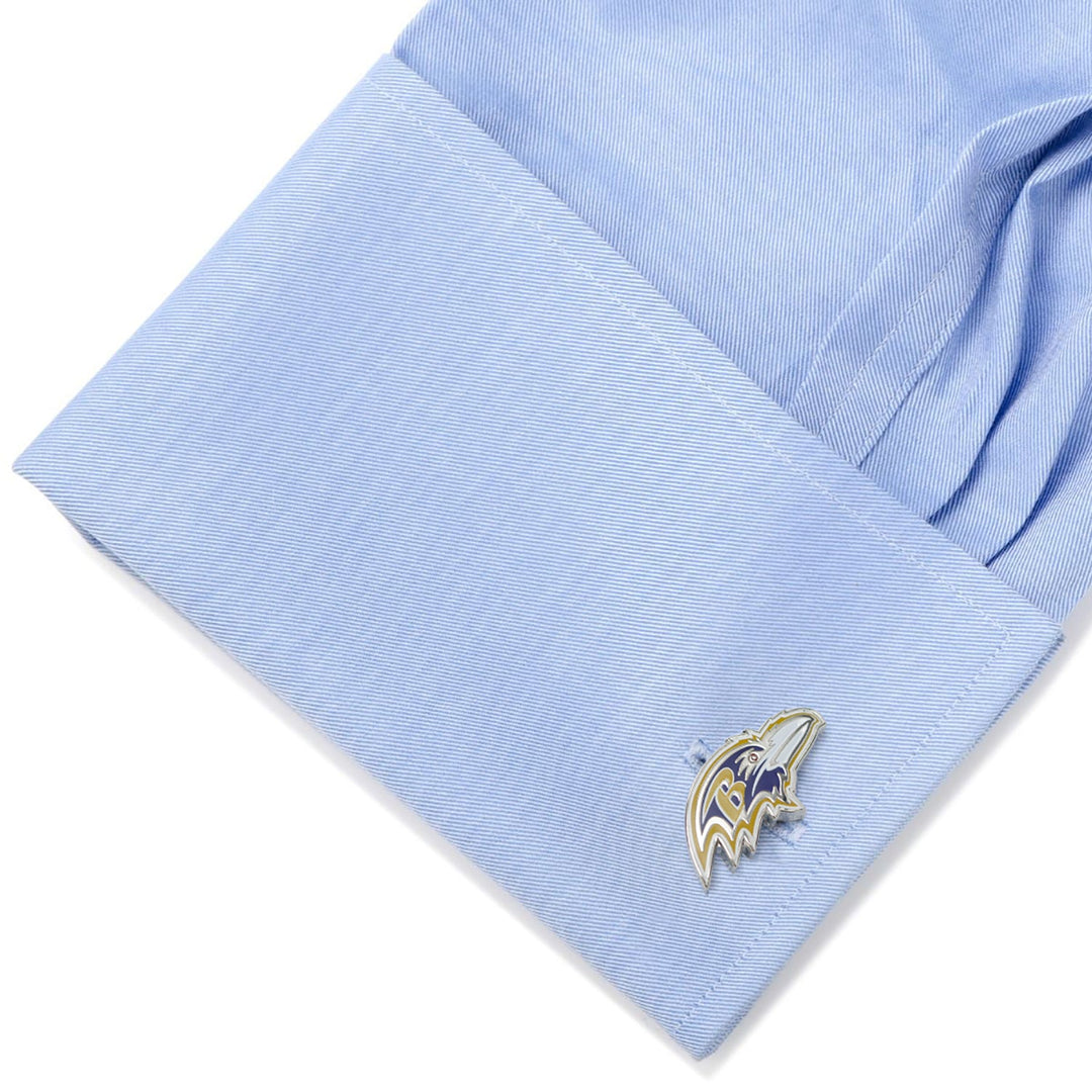 A metal NFL Baltimore Ravens Cufflinks fastened to a light blue dress shirt cuff.