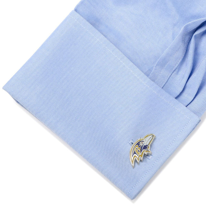 A metal NFL Baltimore Ravens Cufflinks fastened to a light blue dress shirt cuff.