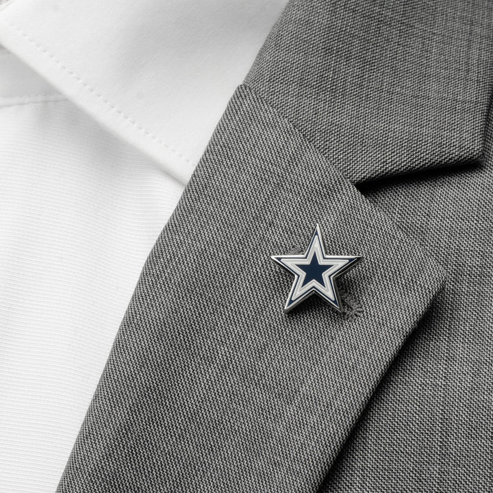 An NFL Dallas Cowboys Lapel Pin in the shape of a star attached to the lapel of a grey suit jacket over a white dress shirt.