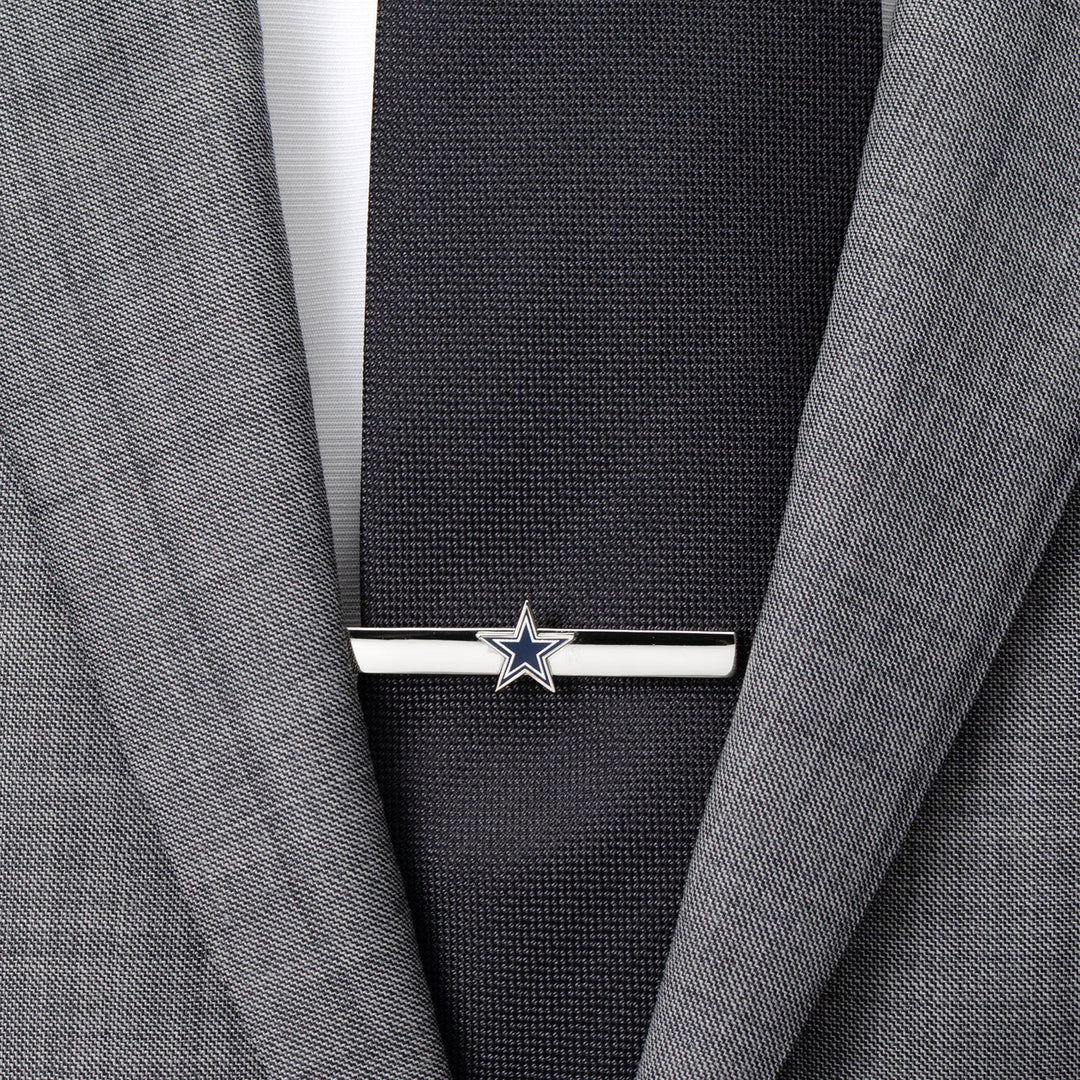 NFL Dallas Cowboys Tie Clip in silver-tone featuring a blue and white star logo, worn on a black necktie and grey suit jacket.