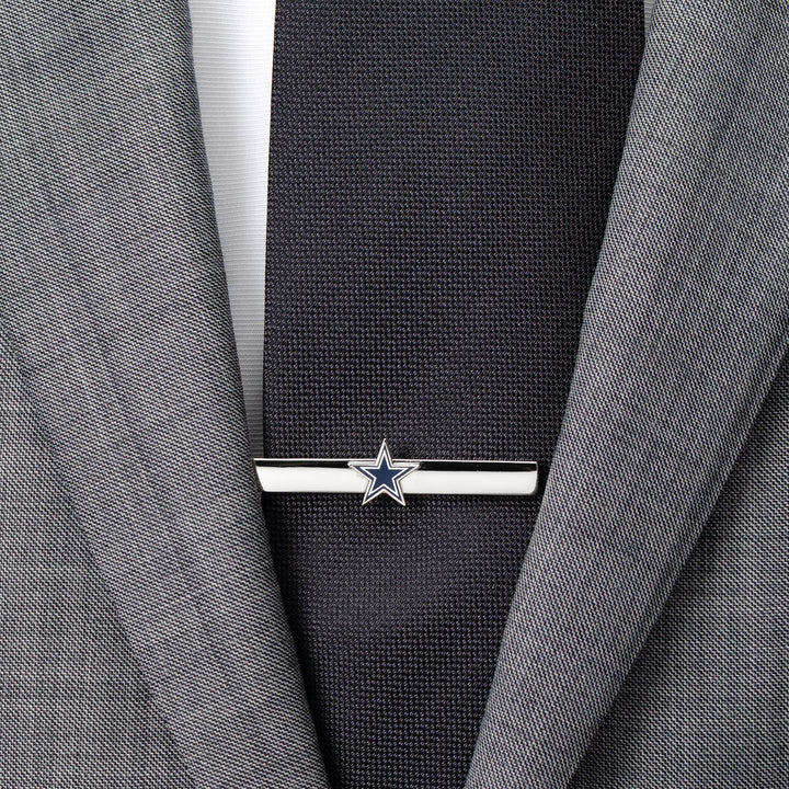 NFL Dallas Cowboys Tie Clip in silver-tone featuring a blue and white star logo, worn on a black necktie and grey suit jacket.