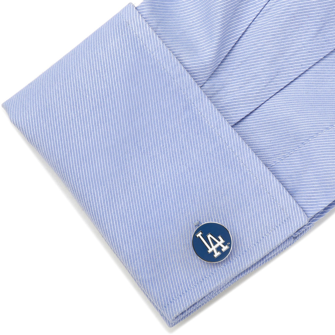 A silver MLB LA Dodgers Cufflinks piece with a blue circular inlay featuring the white LA Dodgers logo, fastened to a light blue dress shirt cuff.