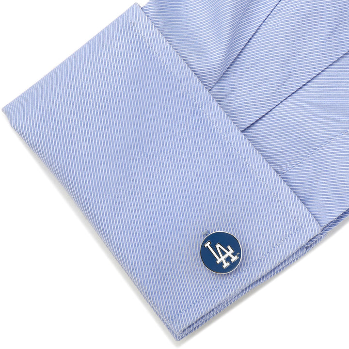 A silver MLB LA Dodgers Cufflinks piece with a blue circular inlay featuring the white LA Dodgers logo, fastened to a light blue dress shirt cuff.