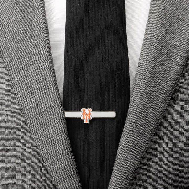 A silver-plated MLB New York Mets Tie Clip featuring the team’s orange and blue “NY” logo, worn on a black tie and grey suit jacket.