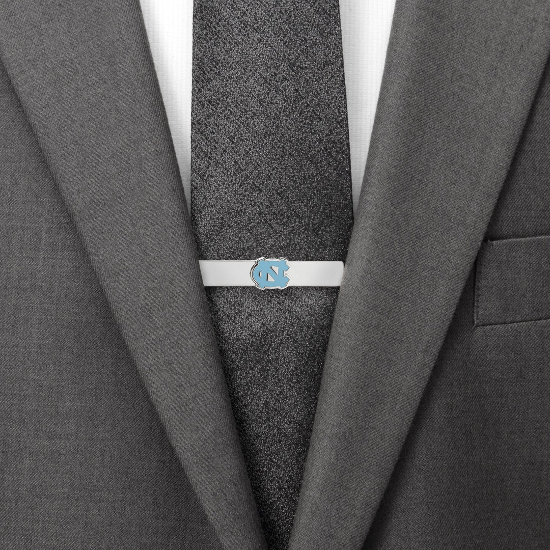 Silver NCAA University of North Carolina Tar Heels Tie Bar attached to a dark textured tie and grey suit jacket.