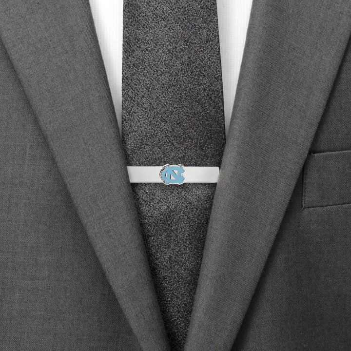 Silver NCAA University of North Carolina Tar Heels Tie Bar attached to a dark textured tie and grey suit jacket.