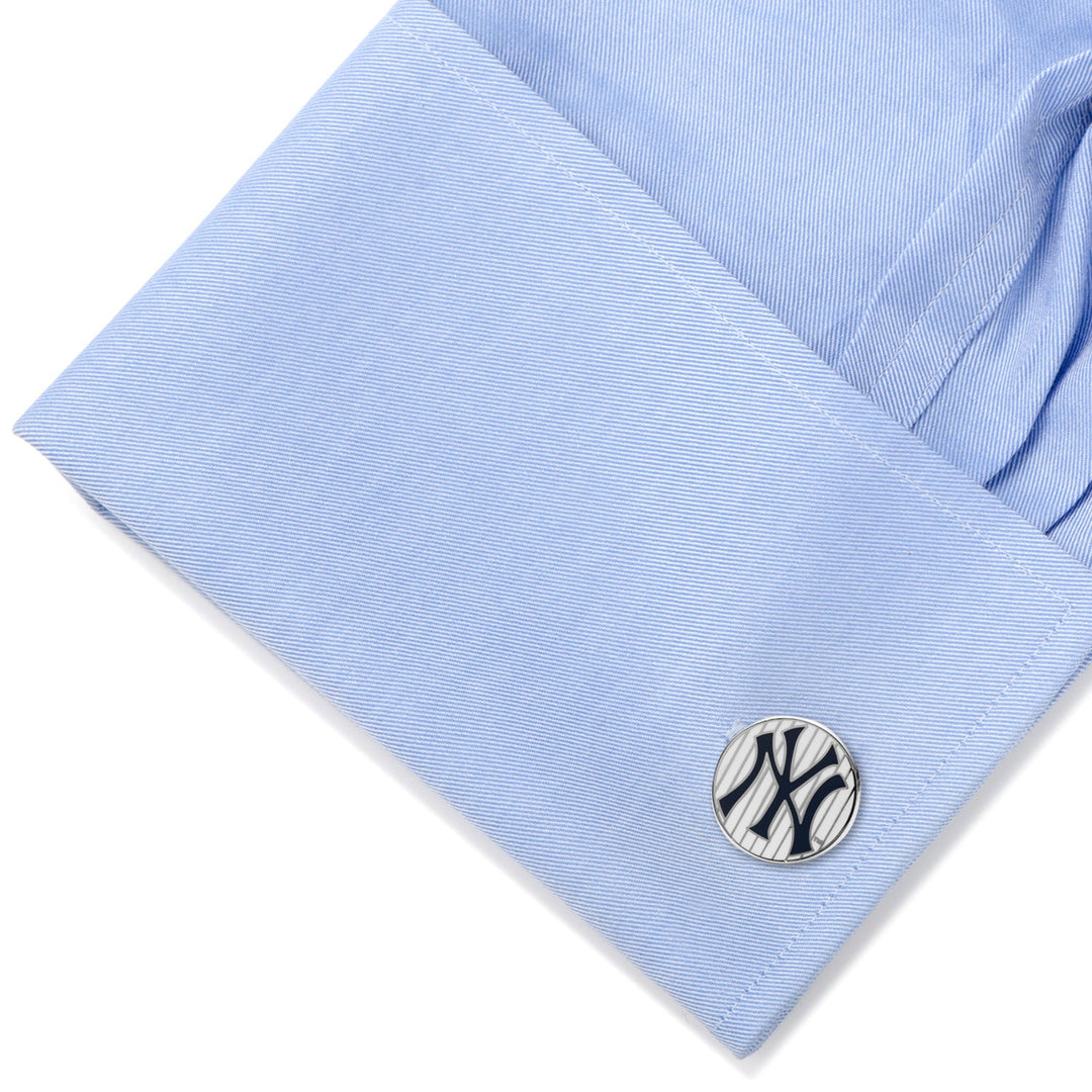 Round silver MLB New York Yankees Pinstripe Cufflinks with a navy blue logo secured on a light blue dress shirt cuff.