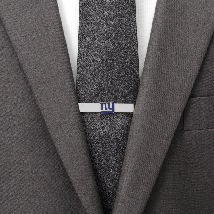 A silver NFL New York Giants Tie Bar featuring the blue “ny” logo, worn on a dark textured tie and grey suit jacket.