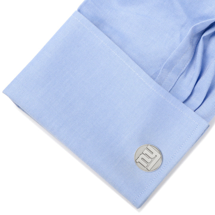 Round silver NFL New York Giants Silver Edition cufflinks on a light blue dress shirt cuff.