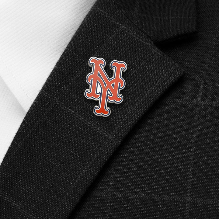 A New York Mets Lapel Pin featuring the team’s orange and blue logo attached to the lapel of a black suit jacket.