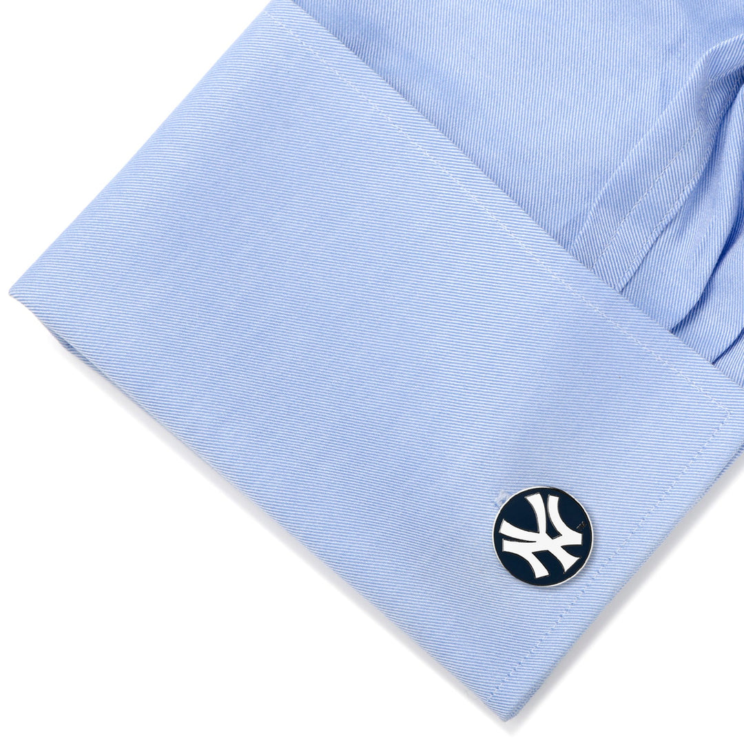 A round MLB New York Yankees Cufflinks set attached to the cuff of a light blue dress shirt.