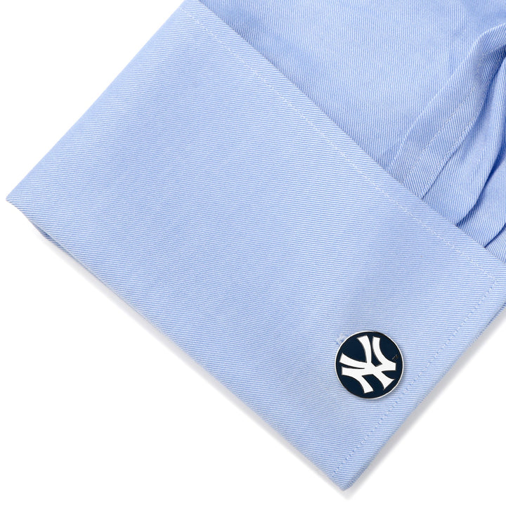 A round MLB New York Yankees Cufflinks set attached to the cuff of a light blue dress shirt.