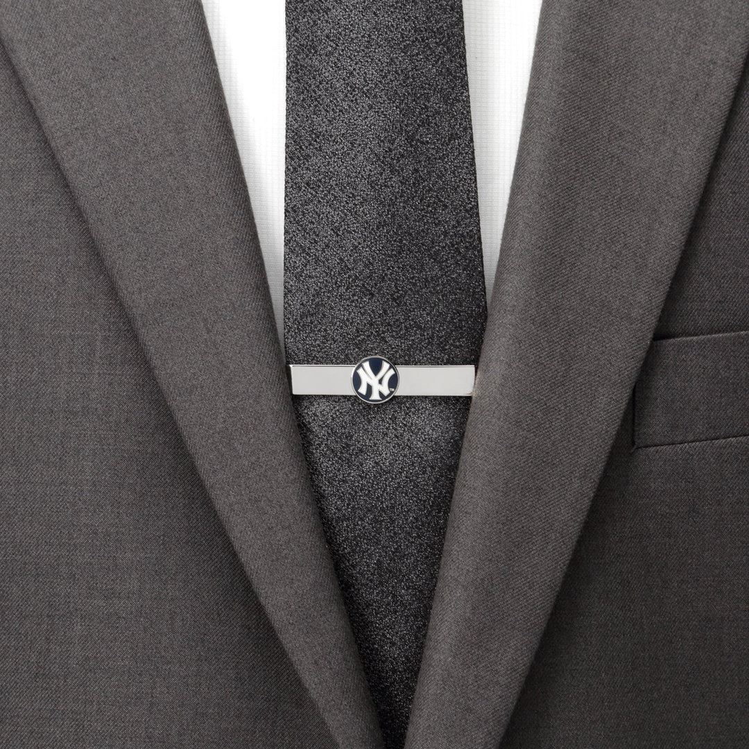 A silver, officially licensed MLB New York Yankees Tie Bar clipped to a dark textured tie and gray suit jacket.